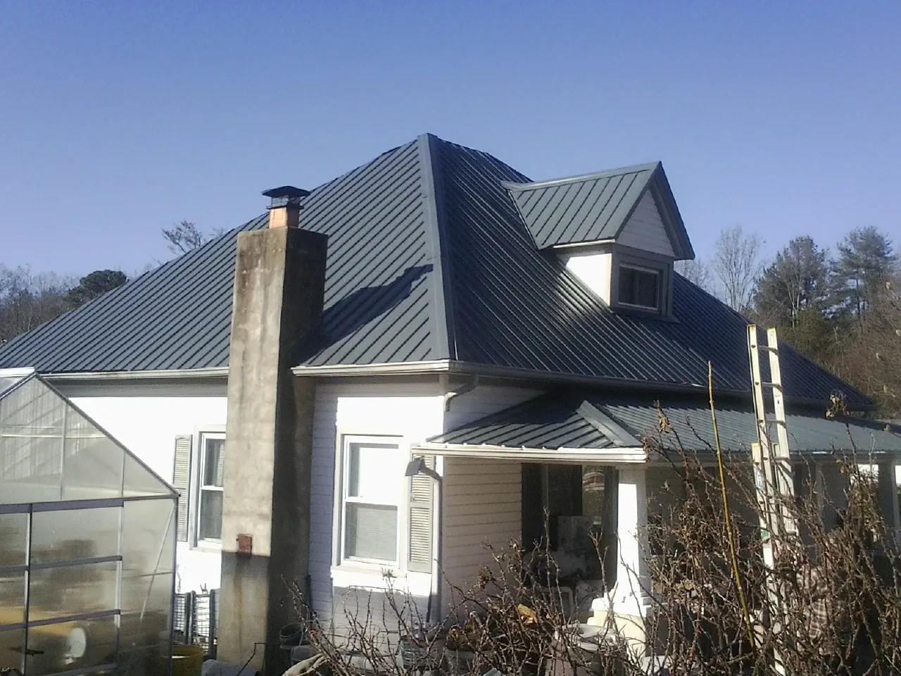 Dark blue standing seam metal roof on a white farmhouse with dormer — Slate & Tile Roof Repair by Roofing Brothers in Bethesda