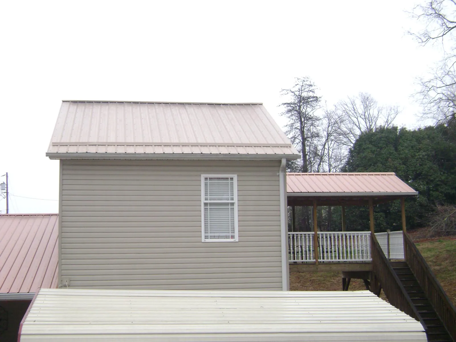 Tan metal roofs on a two story addition and attached porch, from a Roof Replacement job in Bethesda